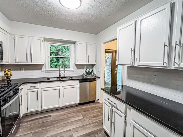 3150 Stratford Green Pl, Avondale Estates, GA 30002 - kitchen with stainless steel dishwasher, gas range, dark countertops, wood finished floors, and white cabinets