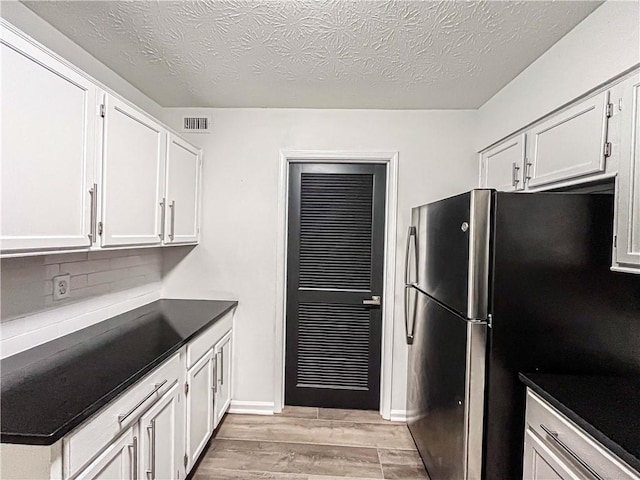 3150 Stratford Green Pl, Avondale Estates, GA 30002 - kitchen featuring light wood-style floors, freestanding refrigerator, white cabinets, backsplash, and dark countertops