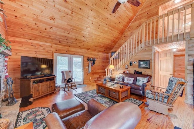 living room featuring hardwood / wood-style floors, high vaulted ceiling, wooden walls, and ceiling fan