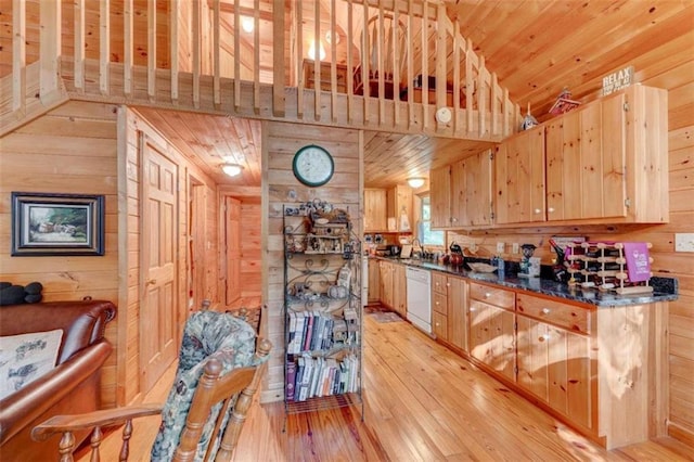 kitchen featuring white dishwasher, wooden walls, and light hardwood / wood-style floors