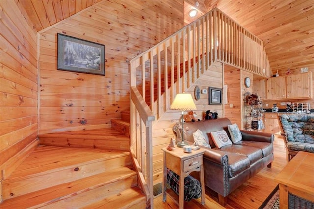 staircase featuring a towering ceiling, hardwood / wood-style flooring, and wooden walls