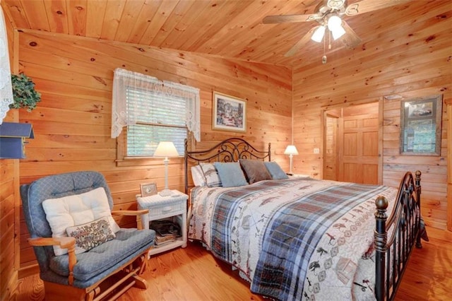 bedroom featuring wooden ceiling, light hardwood / wood-style floors, ceiling fan, vaulted ceiling, and wood walls