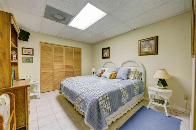 bedroom featuring light tile patterned floors, a paneled ceiling, and a closet