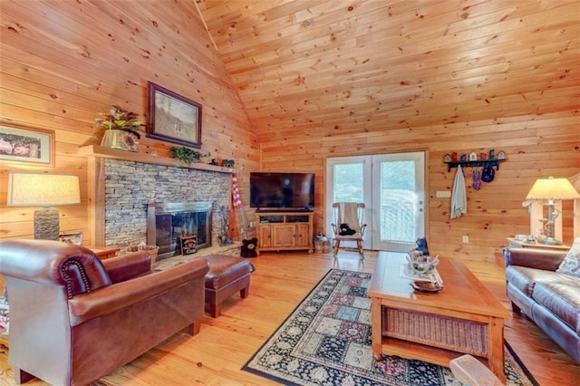 living room featuring high vaulted ceiling, wooden walls, light hardwood / wood-style floors, wooden ceiling, and a fireplace