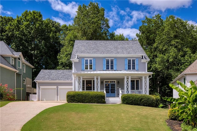 colonial house with a porch, a garage, an outdoor structure, and a front yard