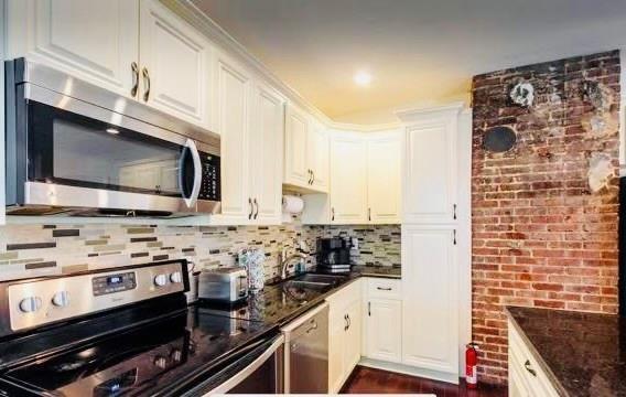 kitchen with white cabinetry, appliances with stainless steel finishes, and dark stone countertops