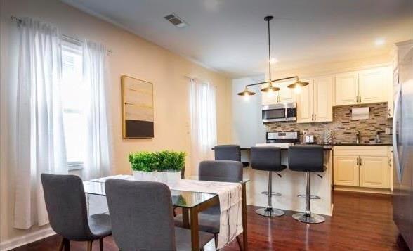 kitchen with pendant lighting, white cabinetry, sink, decorative backsplash, and stainless steel appliances