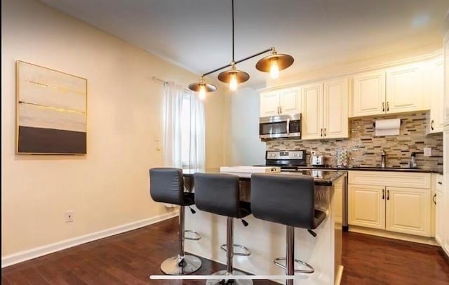 kitchen with sink, appliances with stainless steel finishes, white cabinetry, hanging light fixtures, and tasteful backsplash