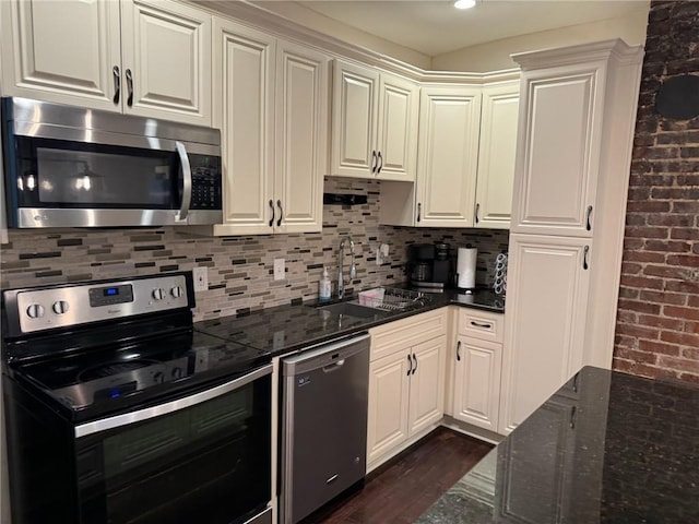 kitchen featuring sink, dark stone counters, dark hardwood / wood-style floors, stainless steel appliances, and decorative backsplash