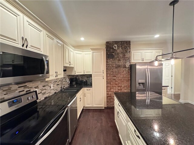 kitchen featuring pendant lighting, sink, appliances with stainless steel finishes, dark stone countertops, and a center island