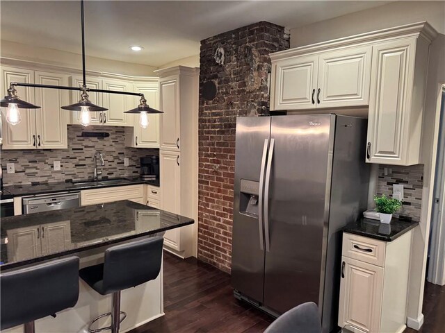 kitchen with pendant lighting, tasteful backsplash, dark stone countertops, white cabinets, and stainless steel appliances