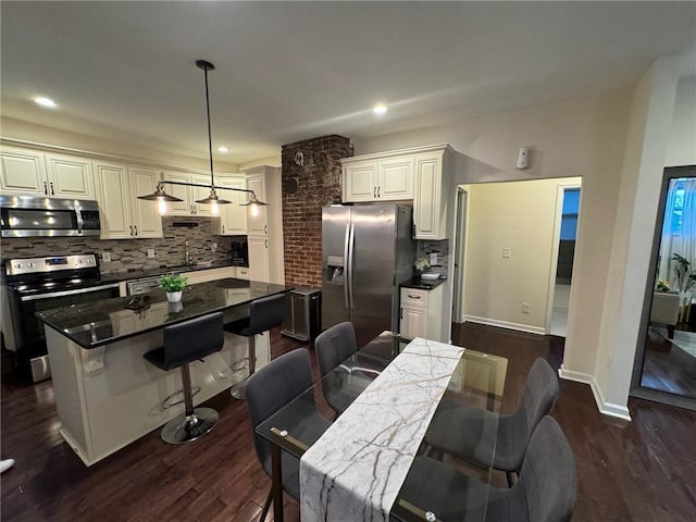 kitchen featuring a kitchen island, appliances with stainless steel finishes, sink, a breakfast bar area, and hanging light fixtures