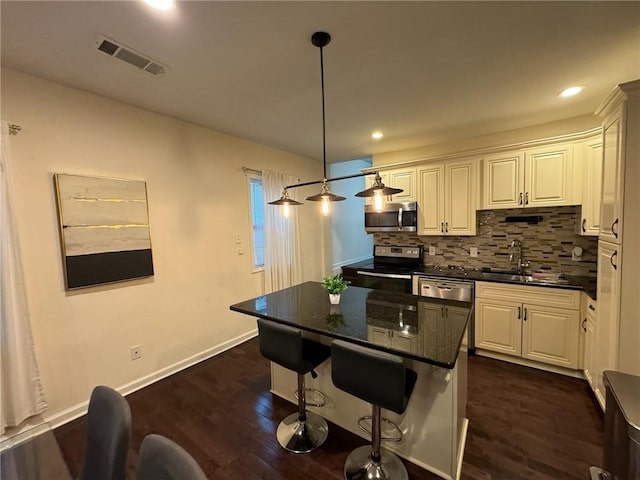 kitchen featuring a kitchen island, white cabinetry, sink, hanging light fixtures, and stainless steel appliances