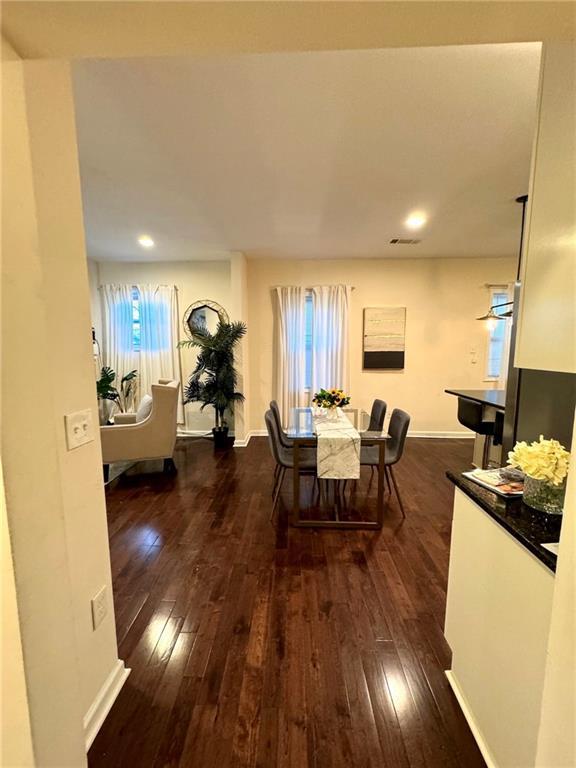 kitchen featuring stainless steel fridge with ice dispenser, dark hardwood / wood-style flooring, pendant lighting, dark stone counters, and white cabinets