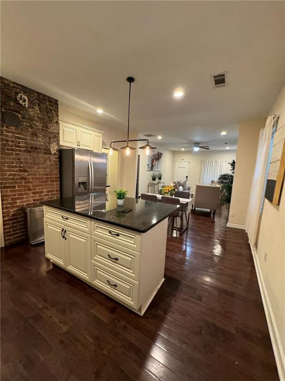 kitchen featuring pendant lighting, stainless steel fridge with ice dispenser, a kitchen island, and white cabinets