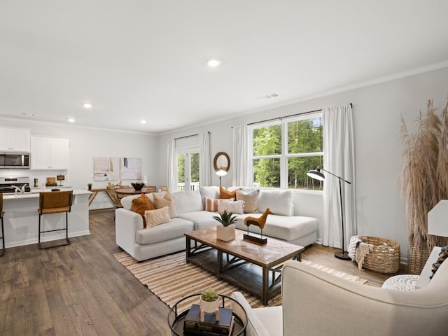 living area featuring dark wood finished floors, ornamental molding, a healthy amount of sunlight, and recessed lighting