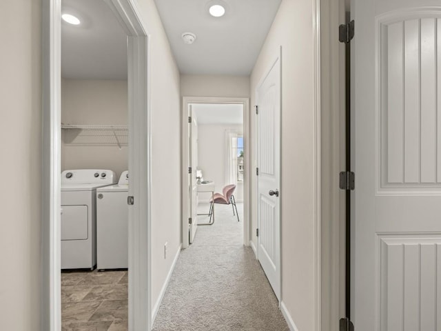 hallway featuring washing machine and dryer, baseboards, and light colored carpet