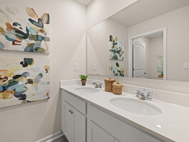 bathroom with double vanity, baseboards, and a sink