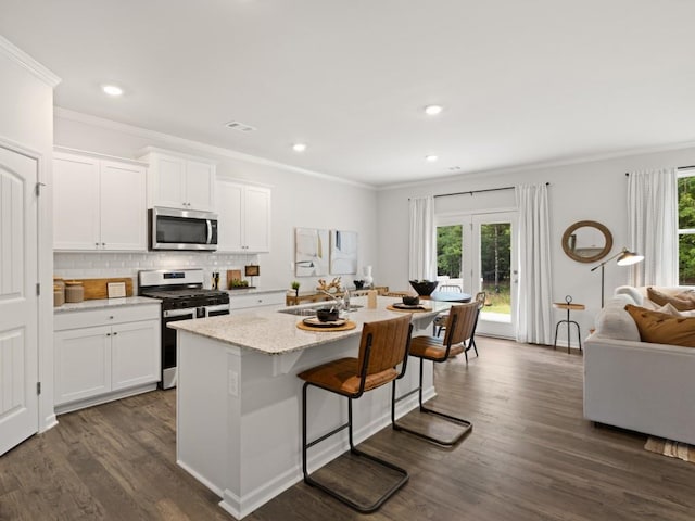 kitchen with crown molding, a sink, a center island with sink, dark wood finished floors, and appliances with stainless steel finishes