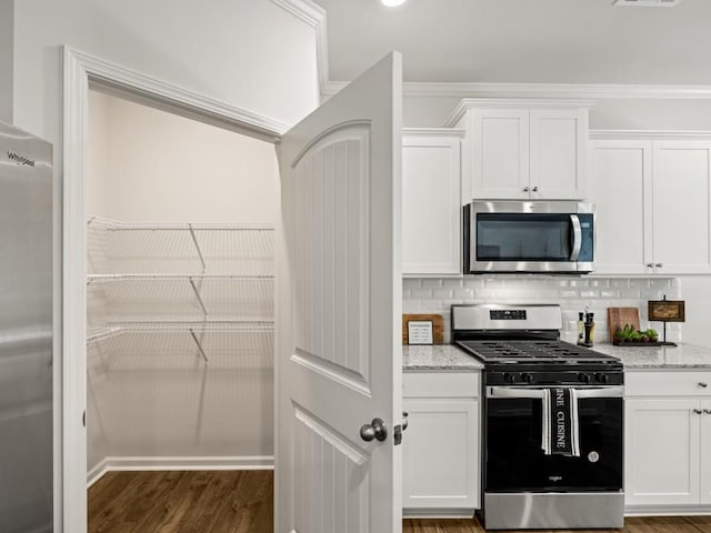 kitchen featuring light stone counters, wood finished floors, white cabinets, backsplash, and appliances with stainless steel finishes