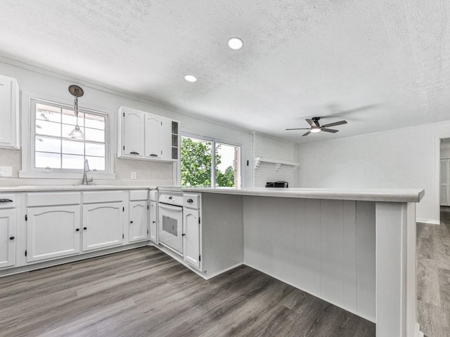 kitchen featuring a textured ceiling, a ceiling fan, white cabinets, dark wood-style flooring, and a sink