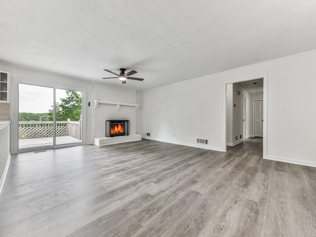unfurnished living room with a ceiling fan, wood finished floors, a fireplace, baseboards, and a textured ceiling