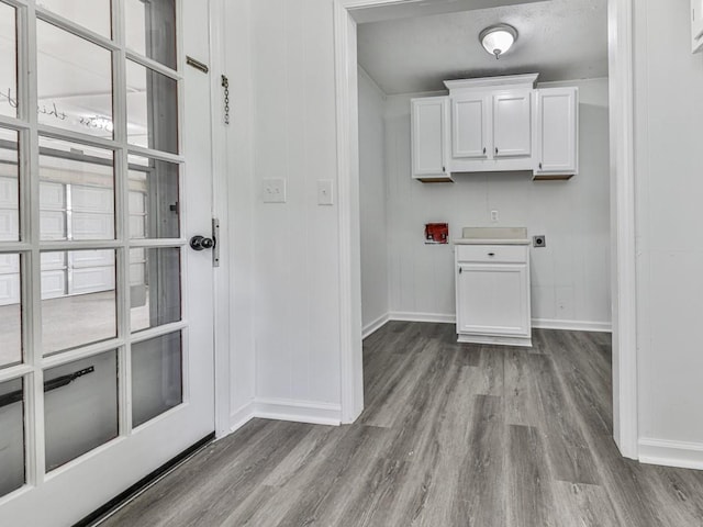 laundry room with electric dryer hookup, baseboards, wood finished floors, and cabinet space