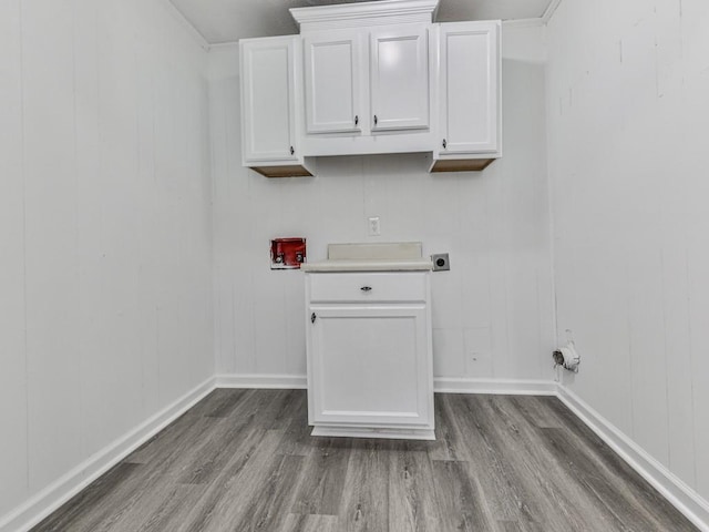 clothes washing area with wood finished floors, electric dryer hookup, baseboards, and a decorative wall