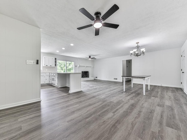 unfurnished living room featuring a ceiling fan, dark wood-style floors, a chandelier, baseboards, and recessed lighting