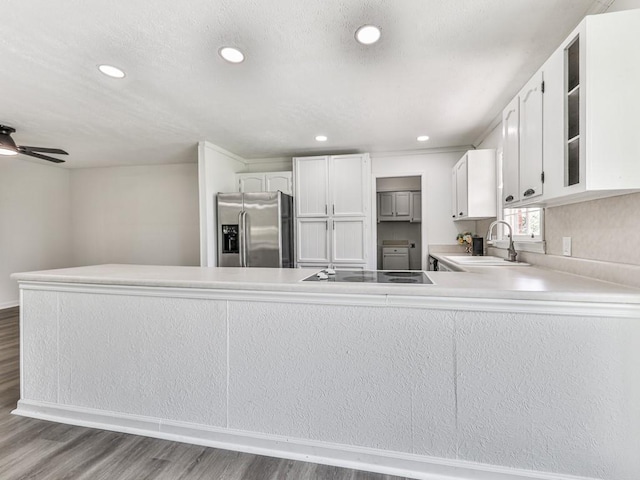 kitchen with stainless steel fridge, a sink, wood finished floors, recessed lighting, and white cabinetry