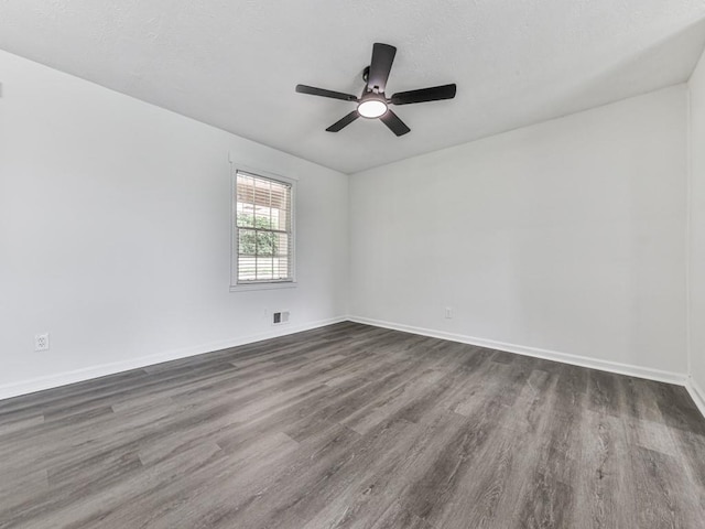 unfurnished room featuring dark wood-type flooring, a ceiling fan, and baseboards