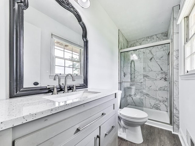 full bathroom featuring a marble finish shower, wood finished floors, toilet, and vanity