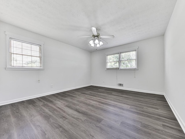 empty room with dark wood finished floors, a textured ceiling, ceiling fan, and baseboards