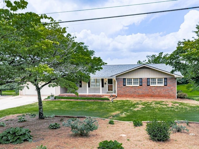 view of front of property featuring brick siding, driveway, a front lawn, a garage, and a porch