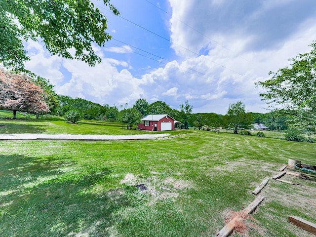 view of grassy yard with an outdoor structure, a detached garage, and a view of rural / pastoral area
