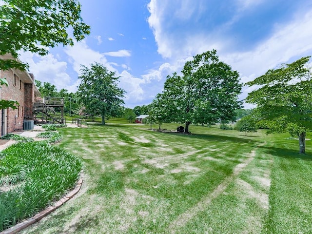 view of grassy yard featuring central air condition unit