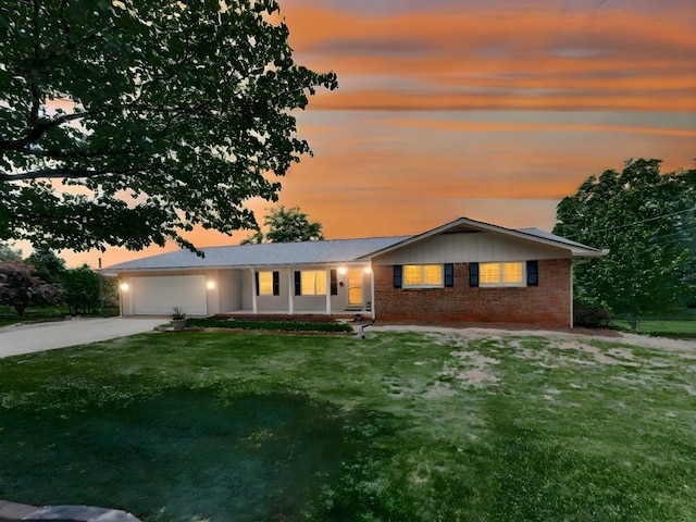 single story home featuring driveway, a garage, a yard, and brick siding