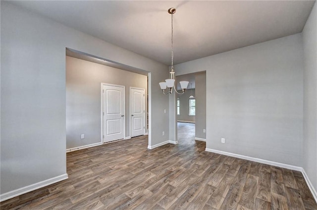 unfurnished dining area featuring an inviting chandelier and dark hardwood / wood-style floors