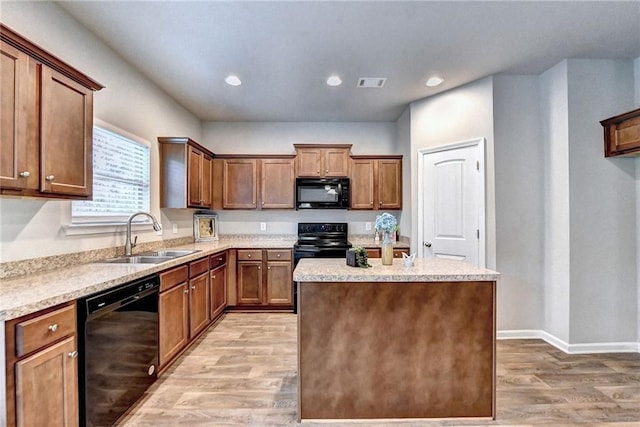 kitchen featuring black appliances, light wood-type flooring, a center island, and sink