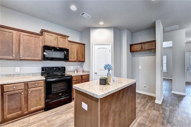 kitchen featuring black appliances, a kitchen island, and hardwood / wood-style floors