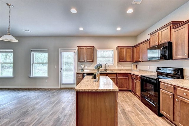 kitchen featuring black appliances, decorative light fixtures, light wood-type flooring, and sink