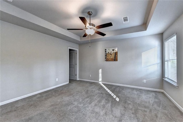 unfurnished room with ceiling fan, carpet floors, and a tray ceiling