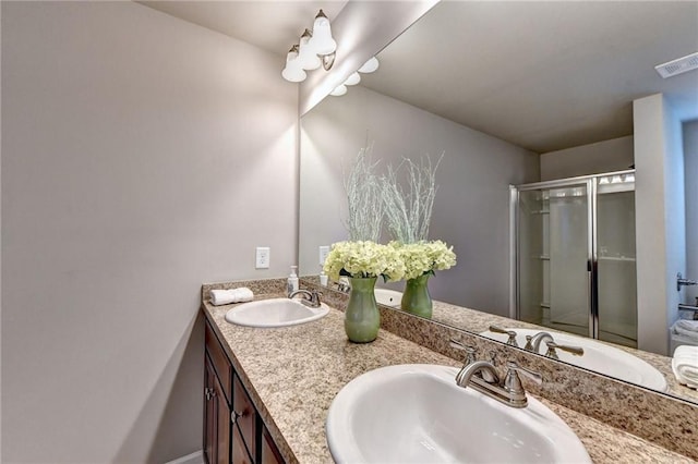 bathroom featuring a shower with door and vanity