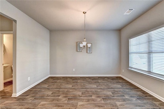 unfurnished dining area with an inviting chandelier and dark wood-type flooring