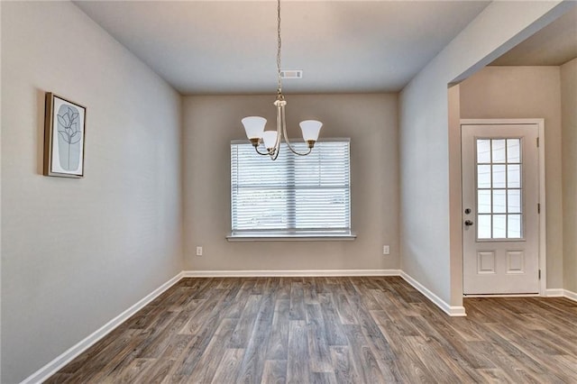 unfurnished dining area featuring dark wood-type flooring and an inviting chandelier