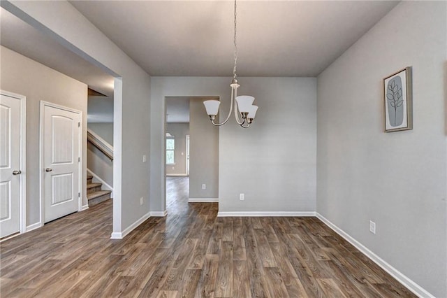 unfurnished dining area featuring dark wood-type flooring and an inviting chandelier