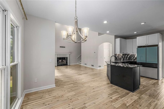 600 Oakmont Hl, Duluth, GA 30097 - kitchen with fridge, arched walkways, dark stone counters, recessed lighting, and light wood finished floors