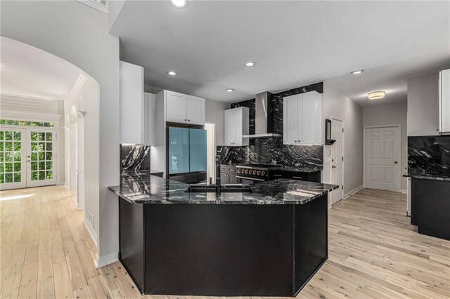 600 Oakmont Hl, Duluth, GA 30097 - kitchen featuring fridge, wall chimney range hood, arched walkways, dark stone counters, and recessed lighting