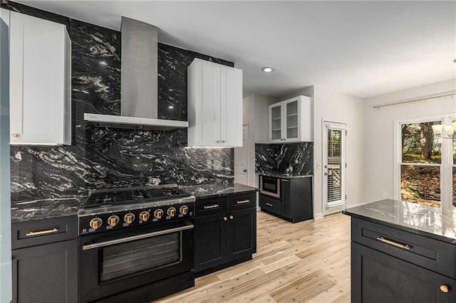 600 Oakmont Hl, Duluth, GA 30097 - kitchen with high end range, wall chimney range hood, white cabinetry, backsplash, and light wood finished floors