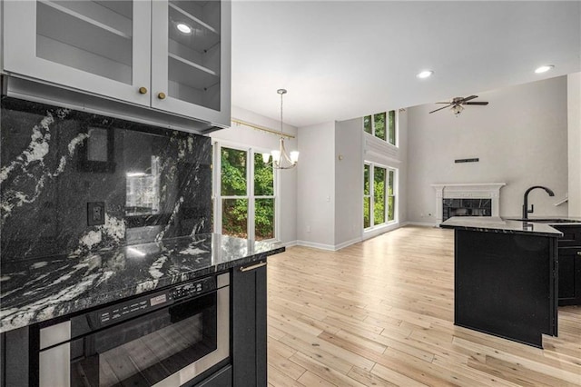 600 Oakmont Hl, Duluth, GA 30097 - kitchen featuring a fireplace, dark cabinets, a chandelier, tasteful backsplash, and dark stone counters